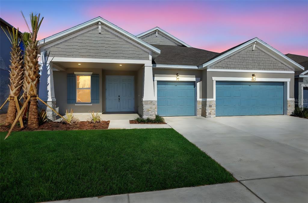 A single-story house exterior features a gray facade, blue garage doors, and a front porch — 17429 VALLEYWOOD PARKWAY, LAND O LAKES, FL