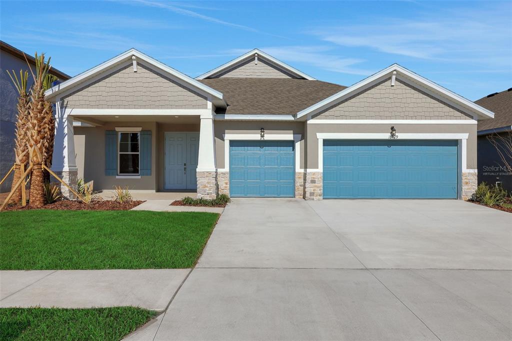 A single-story house features a three-car garage, stone accents, and blue shutters — 17429 VALLEYWOOD PARKWAY, LAND O LAKES, FL