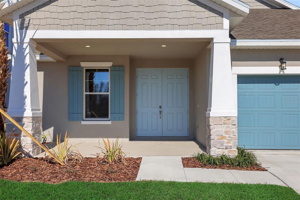 The exterior of a house features a covered porch, light blue double doors, and shutters — 17429 VALLEYWOOD PARKWAY, LAND O LAKES, FL