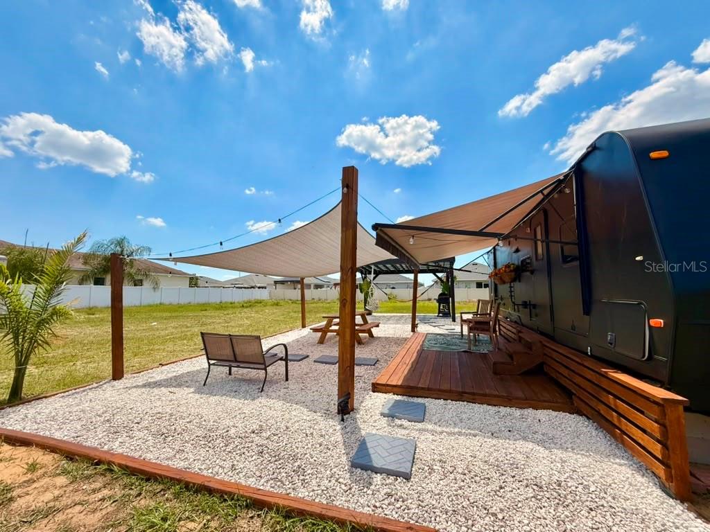 An outdoor living space features a gravel patio, wooden deck, shade sail, and a parked RV — 4040 N 10TH STREET, HAINES CITY, FL