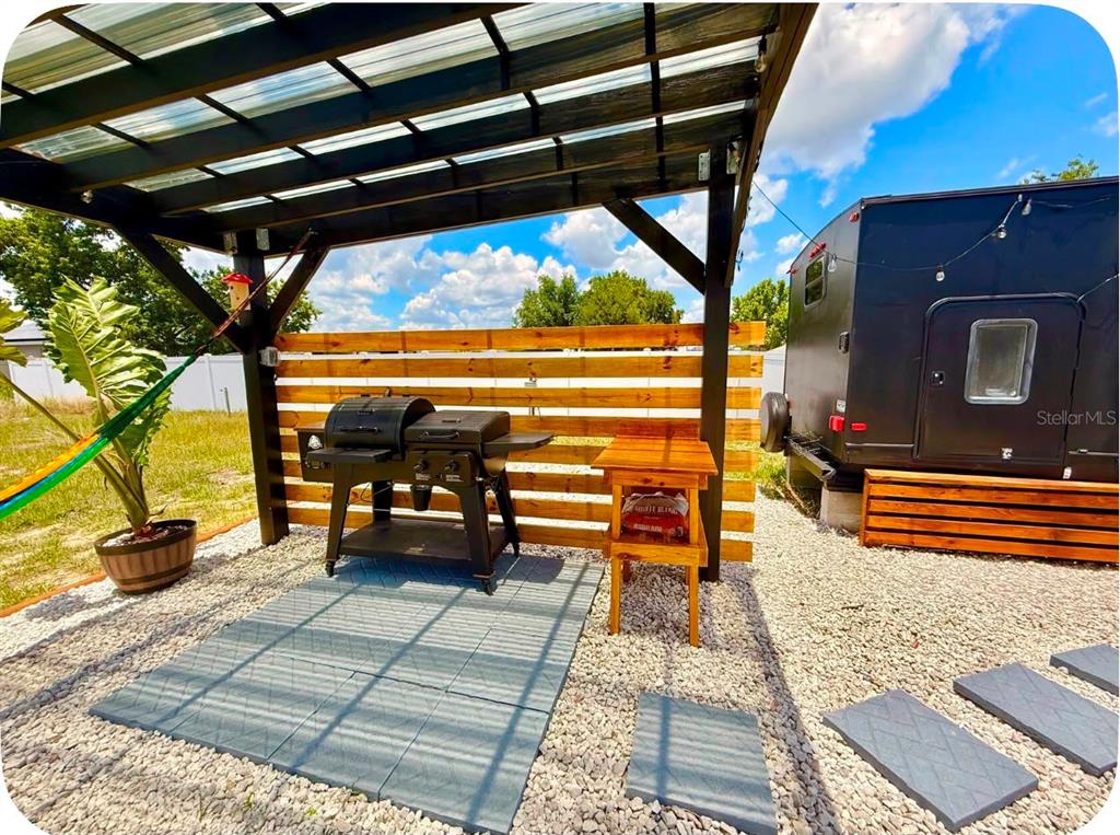 An outdoor patio features a grill, a wooden side table, and a pergola over gravel — 4040 N 10TH STREET, HAINES CITY, FL