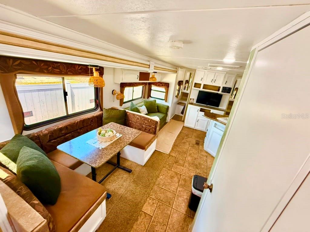 An interior view of a travel trailer featuring a dining booth, sofa, and kitchen area — 4040 N 10TH STREET, HAINES CITY, FL