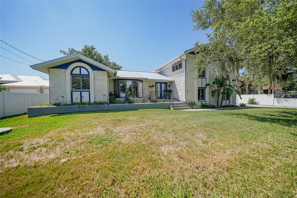 A two-story house with a stone facade, blue trim, and a large front lawn — 4460 NORTHSHORE DRIVE, PUNTA GORDA, FL