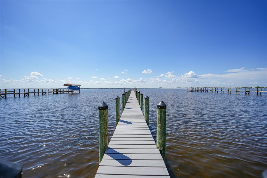 A wooden dock extends into a calm body of water under a clear blue sky — 4460 NORTHSHORE DRIVE, PUNTA GORDA, FL