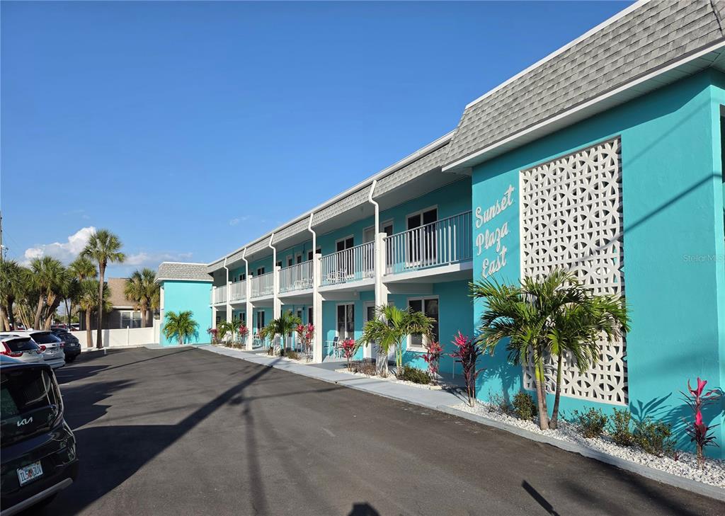 The exterior of a two-story turquoise motel building with a parking lot in front — 680 71ST AVENUE UNIT 11-A, ST PETE BEACH, FL