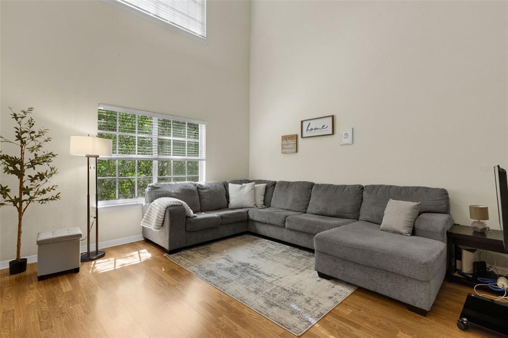 An open-concept living and dining area features a wooden table, gray sofa, and kitchen island — 9872 MEADOW FIELD CIRCLE UNIT 503, TAMPA, FL