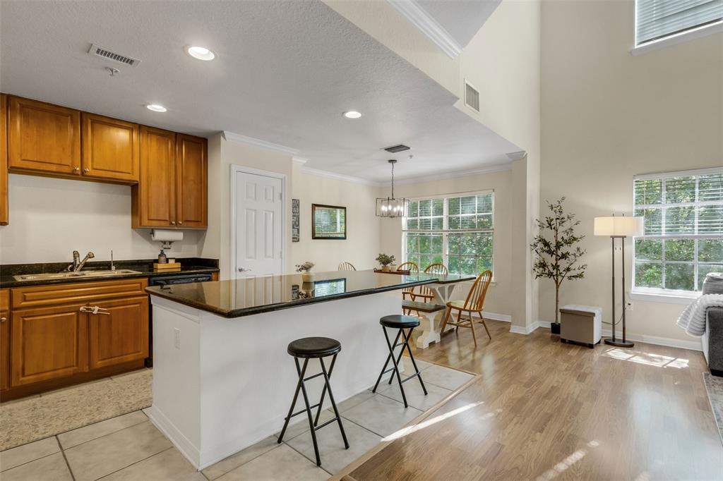 A kitchen with wood cabinets, a white island, and a dining area with large windows — 9872 MEADOW FIELD CIRCLE UNIT 503, TAMPA, FL