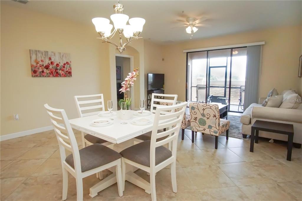 A dining area with a white table and chairs sits adjacent to a living room — 1241 LONG COVE LOOP, DAVENPORT, FL
