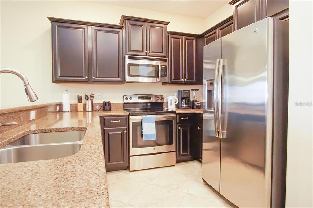 A kitchen features dark wood cabinets, stainless steel appliances, and granite countertops — 1241 LONG COVE LOOP, DAVENPORT, FL