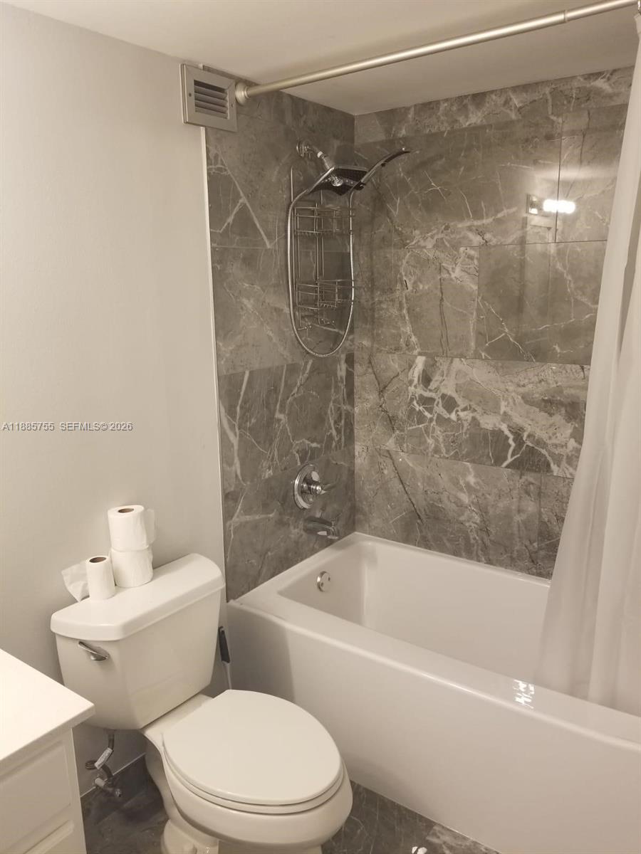 A bathroom features a white toilet, a bathtub, and gray marble-patterned wall tiles — 501 E Three Islands Blvd # 417, Hallandale Beach FL 33009, HALLANDALE BEACH, FL