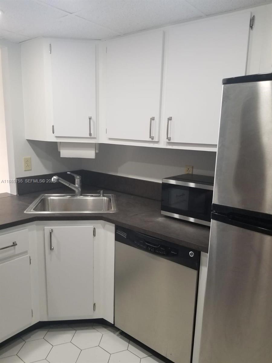 A kitchen features white cabinets, a stainless steel sink, a dishwasher, and a microwave — 501 E Three Islands Blvd # 417, Hallandale Beach FL 33009, HALLANDALE BEACH, FL