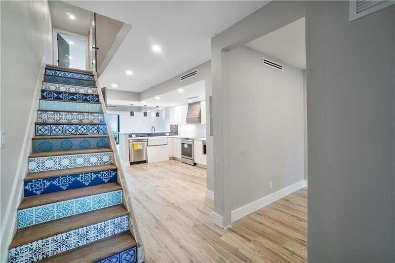 A staircase with patterned blue and white risers leads toward an open-concept kitchen — 520 N Ocean Boulevard # 2, Pompano Beach FL 33062, POMPANO BEACH, FL