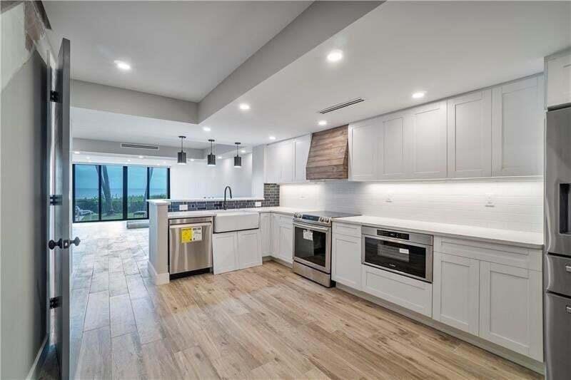 A modern kitchen with white cabinets, stainless steel appliances, and wood-look tile flooring — 520 N Ocean Boulevard # 2, Pompano Beach FL 33062, POMPANO BEACH, FL