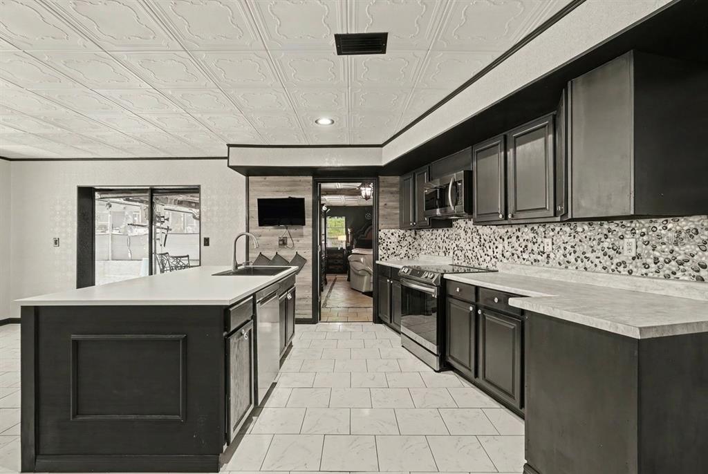 A kitchen with black cabinets, a white island, patterned backsplash, and a white tiled ceiling — 9027 BONNET WAY, WEEKI WACHEE, FL