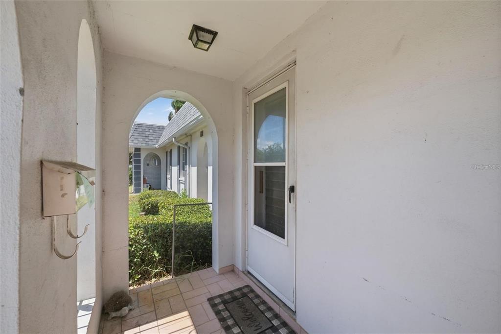 A covered entryway features a white door, a tiled floor, and an arched opening — 4209 TOUCHTON PLACE, NEW PORT RICHEY, FL