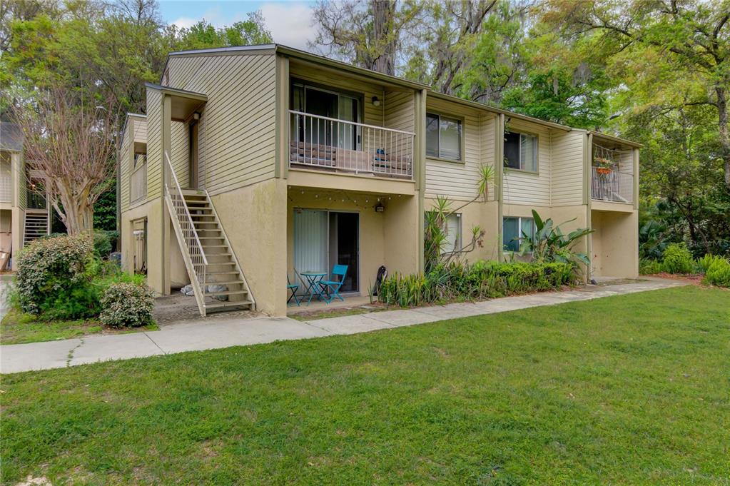 A two-story apartment building with beige siding, stucco lower walls, and an exterior staircase — 1015 SW 9TH STREET UNIT D1, GAINESVILLE, FL