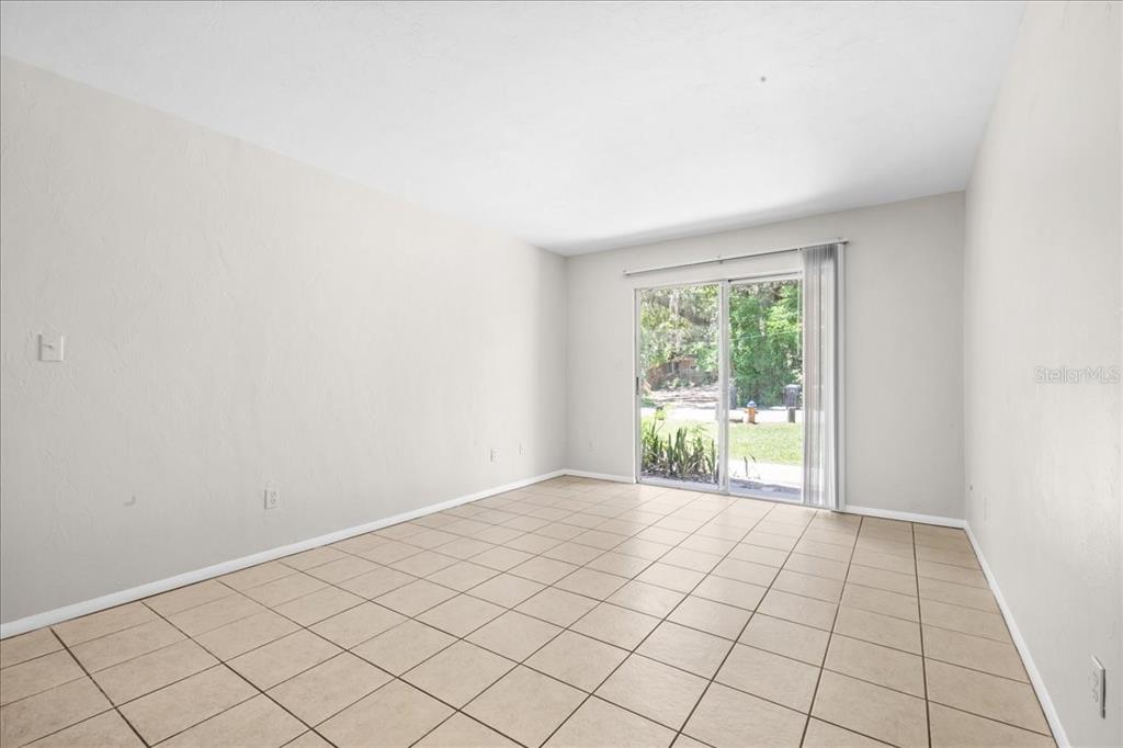 An empty room with light-colored walls, tile flooring, and a sliding glass door — 1015 SW 9TH STREET UNIT D1, GAINESVILLE, FL