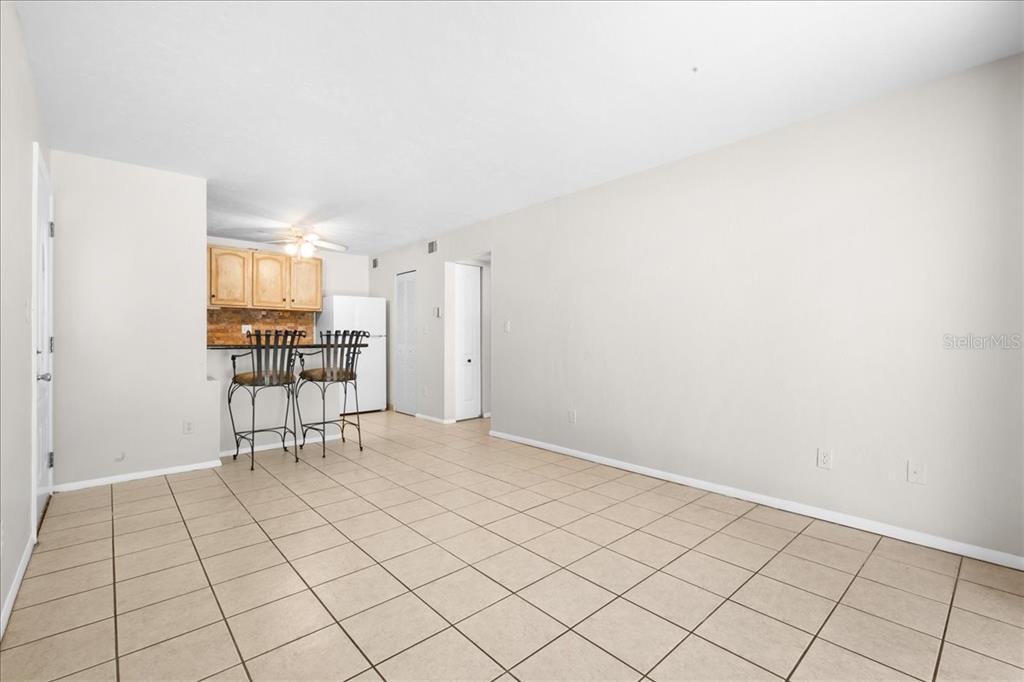 An open-concept room features light-colored tile flooring, beige walls, and a small kitchen area — 1015 SW 9TH STREET UNIT D1, GAINESVILLE, FL