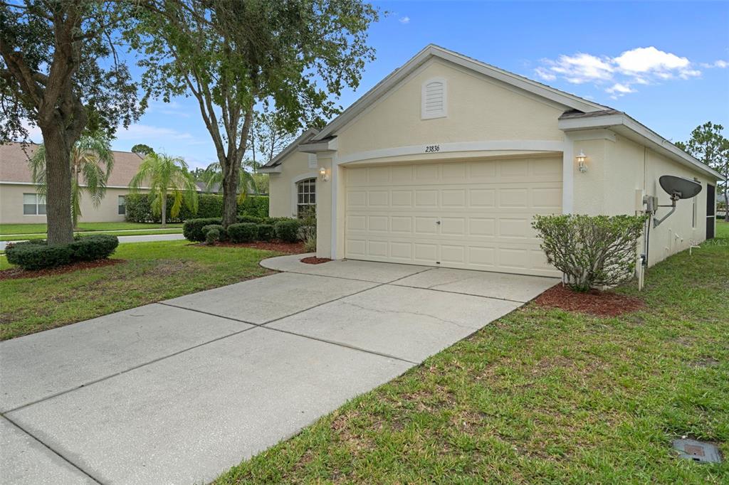 A beige single-story house features a two-car garage, a concrete driveway, and a grassy lawn — 23836 HASTINGS  WAY, LAND O LAKES, FL