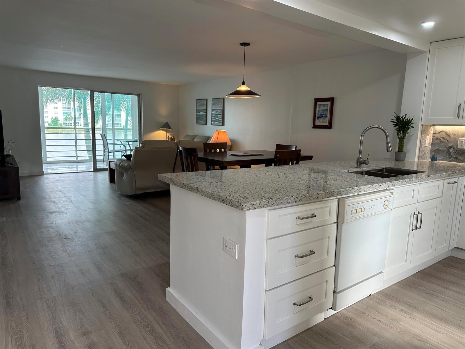 A kitchen island with granite countertops overlooks an open-concept dining and living area — 141 SE 3rd Avenue # 203, Dania Beach FL 33004, DANIA BEACH, FL