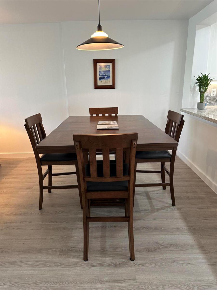 A dining room features a square wooden table with four chairs under a pendant light — 141 SE 3rd Avenue # 203, Dania Beach FL 33004, DANIA BEACH, FL