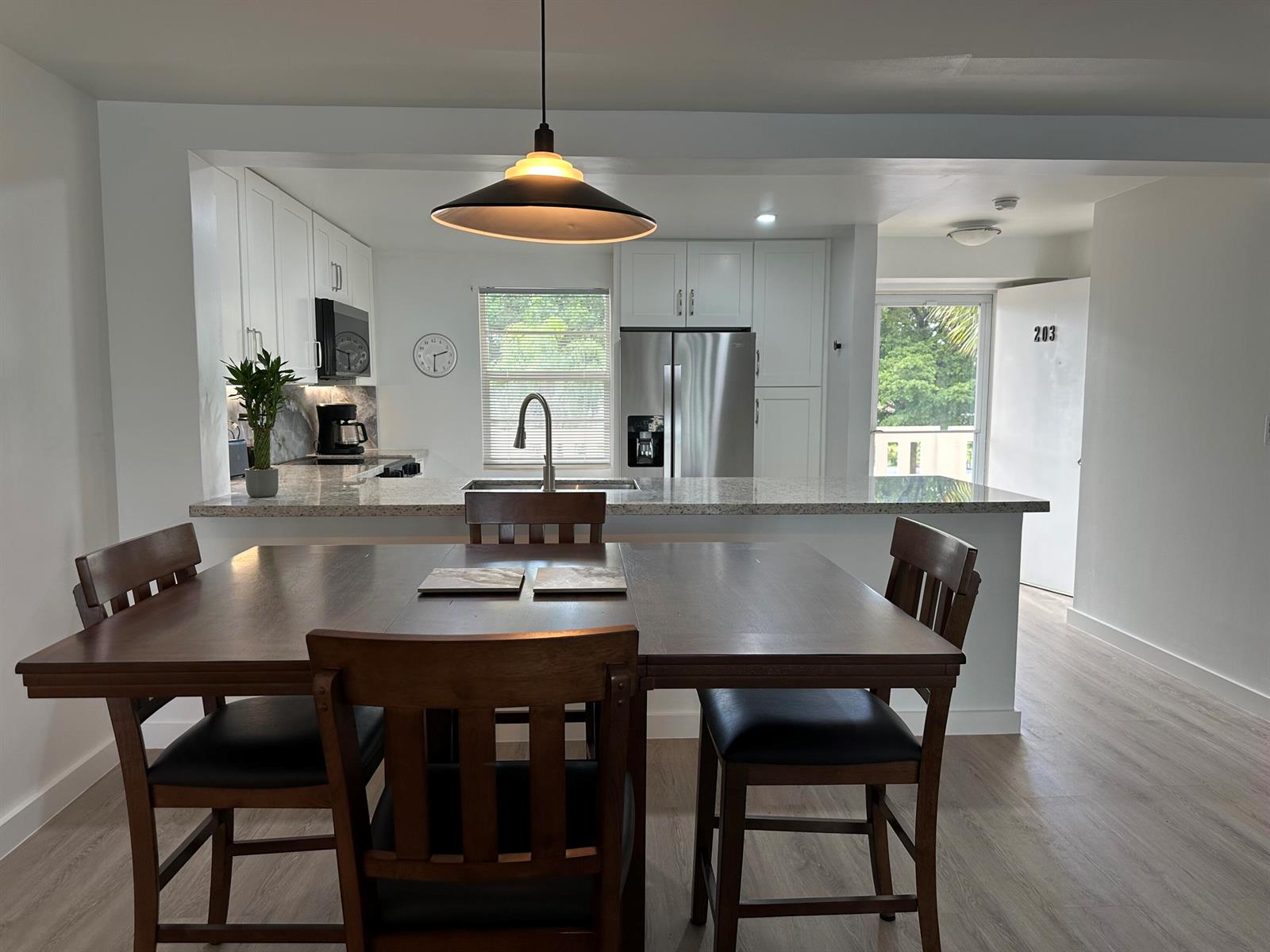A dining area with a wooden table and chairs sits before an open-concept kitchen — 141 SE 3rd Avenue # 203, Dania Beach FL 33004, DANIA BEACH, FL