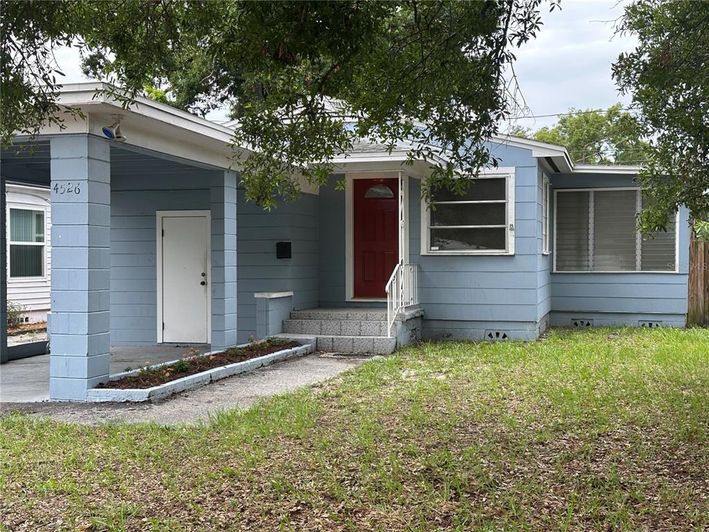 A blue house with a red front door, a carport, and a small front lawn — 4526 6TH AVENUE N, ST PETERSBURG, FL