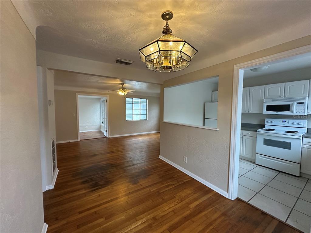 A dining area with hardwood floors connects to a kitchen and a living room — 4526 6TH AVENUE N, ST PETERSBURG, FL
