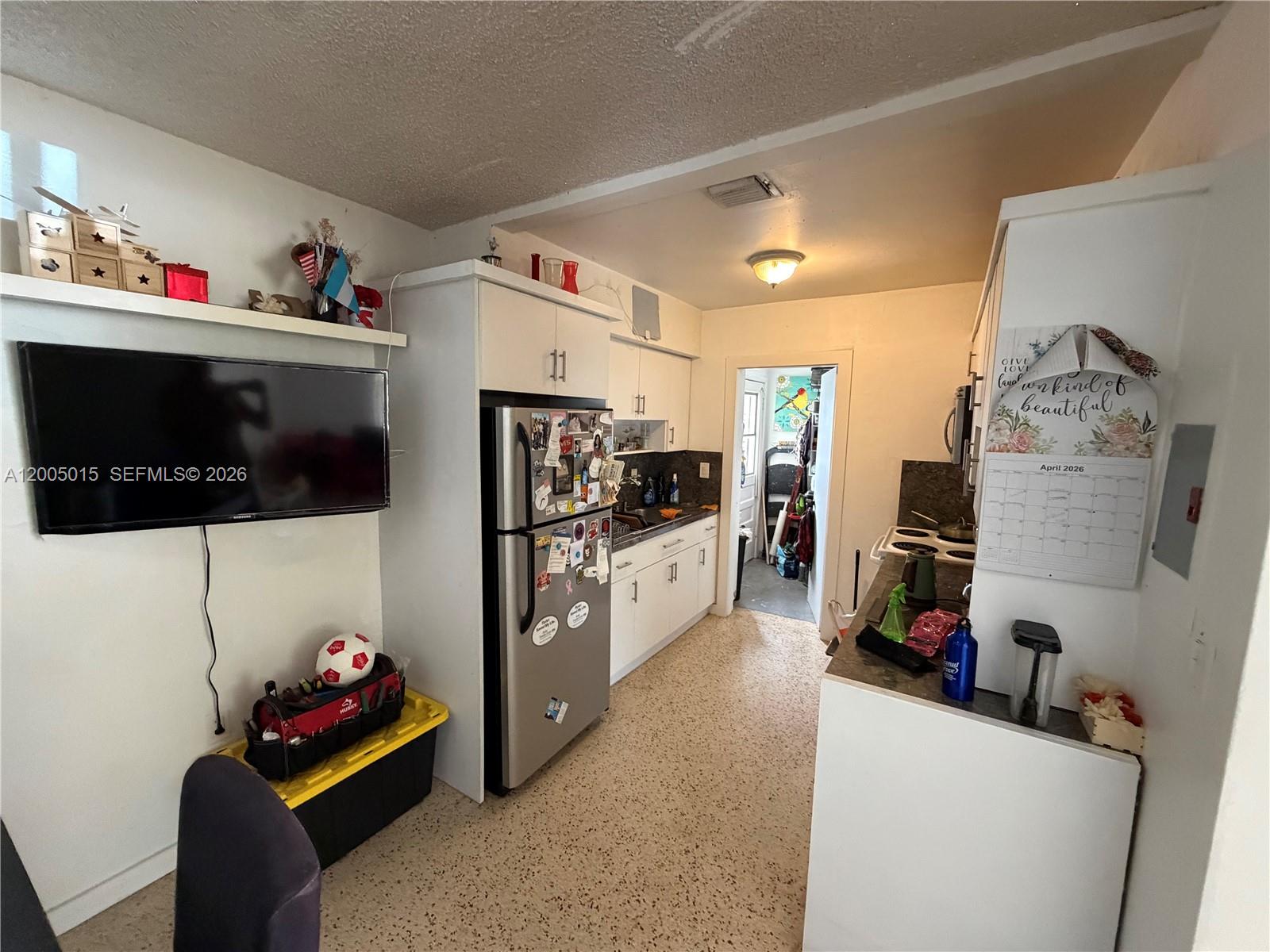 A kitchen with white cabinets, stainless steel appliances, and a television mounted on the wall — 3361 SW 28th St, Miami FL 33133, MIAMI, FL