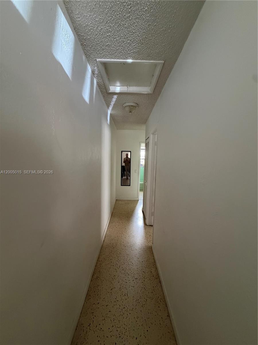 A narrow hallway features white walls, a textured ceiling, and speckled vinyl flooring — 3361 SW 28th St, Miami FL 33133, MIAMI, FL