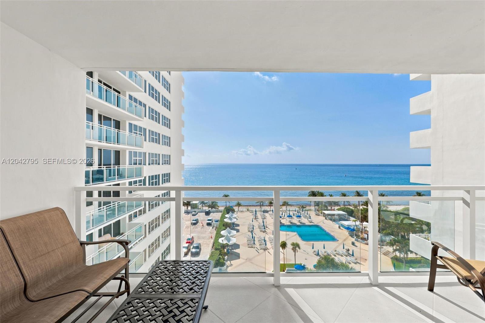 A balcony with outdoor furniture overlooks a swimming pool, beach, and the ocean — 2030 S Ocean Dr # 816, Hallandale Beach FL 33009, HALLANDALE BEACH, FL