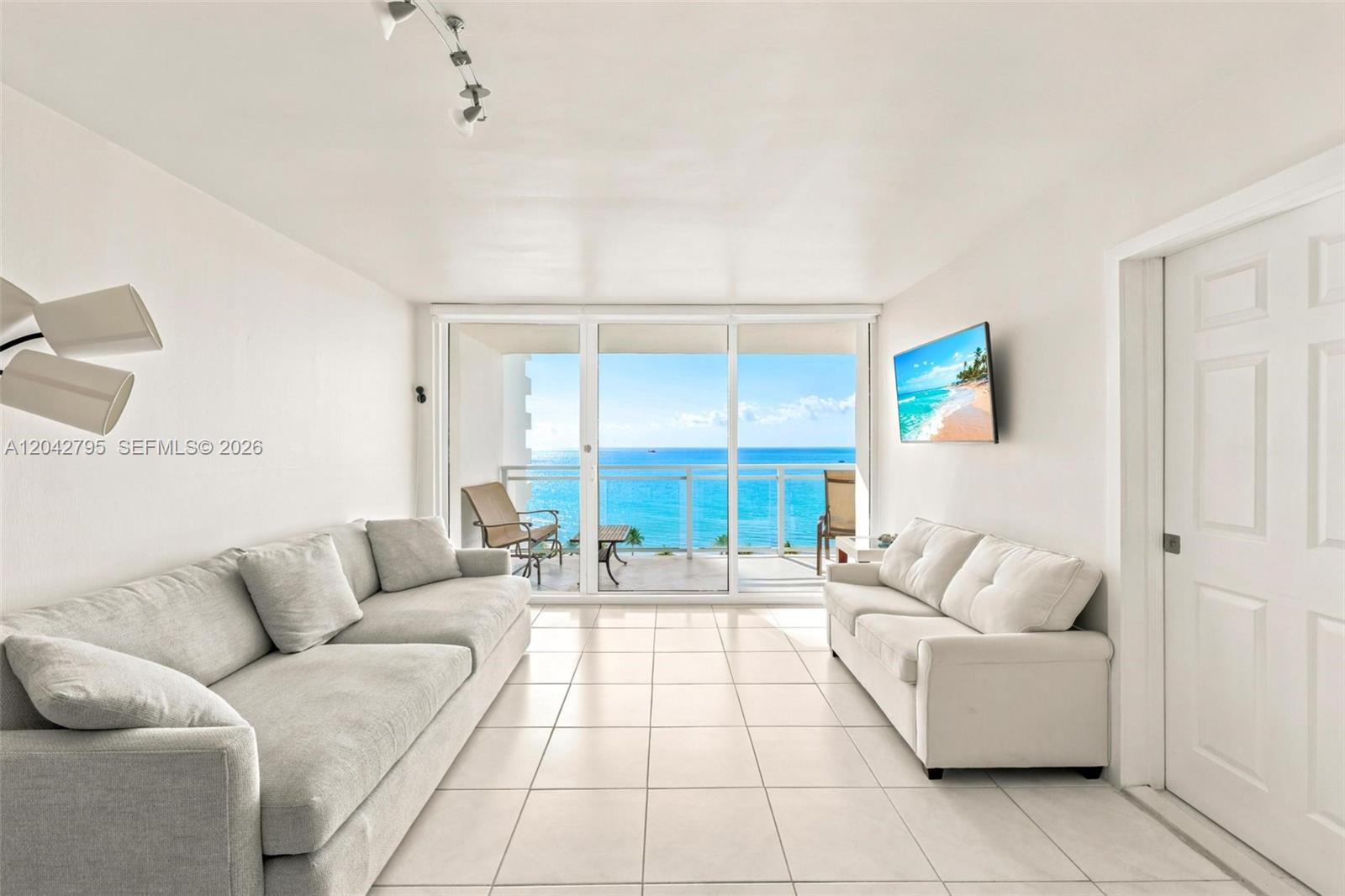 A living room features two sofas, tile flooring, and a balcony overlooking the ocean — 2030 S Ocean Dr # 816, Hallandale Beach FL 33009, HALLANDALE BEACH, FL
