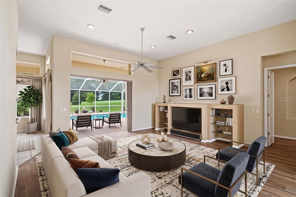 A living room with a large television, built-in shelving, and sliding doors opening to a pool — 926 E TRIPLE CROWN LOOP, HERNANDO, FL