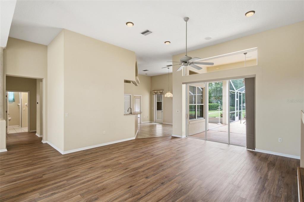 An open living area features wood-look flooring, high ceilings, a ceiling fan, and sliding glass doors — 926 E TRIPLE CROWN LOOP, HERNANDO, FL