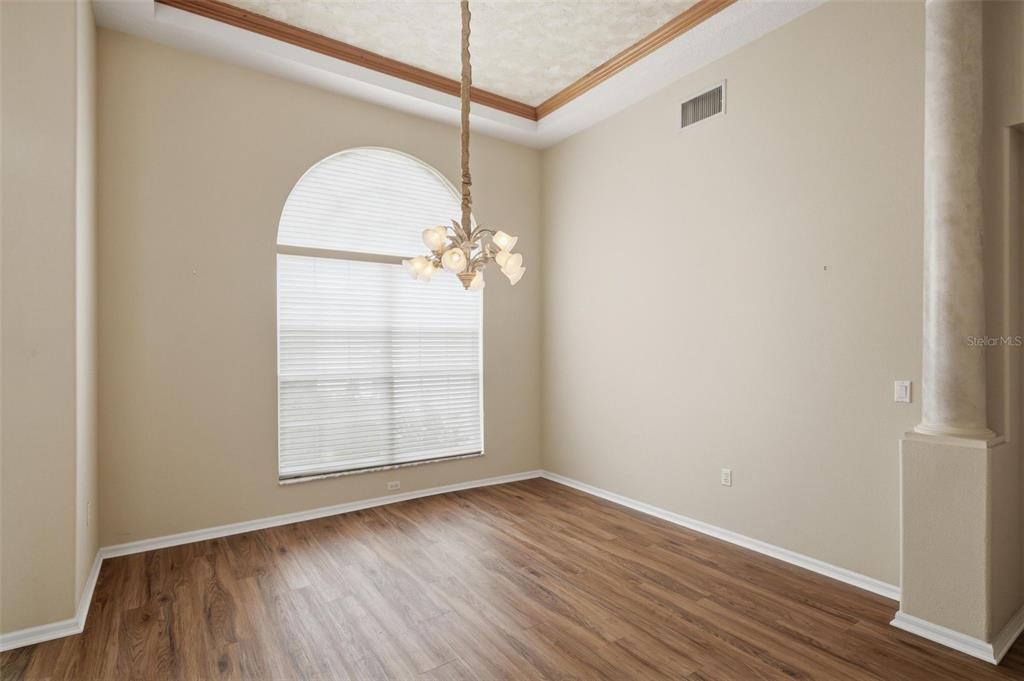 An empty dining room features wood-look flooring, a vaulted ceiling, and an arched window — 926 E TRIPLE CROWN LOOP, HERNANDO, FL