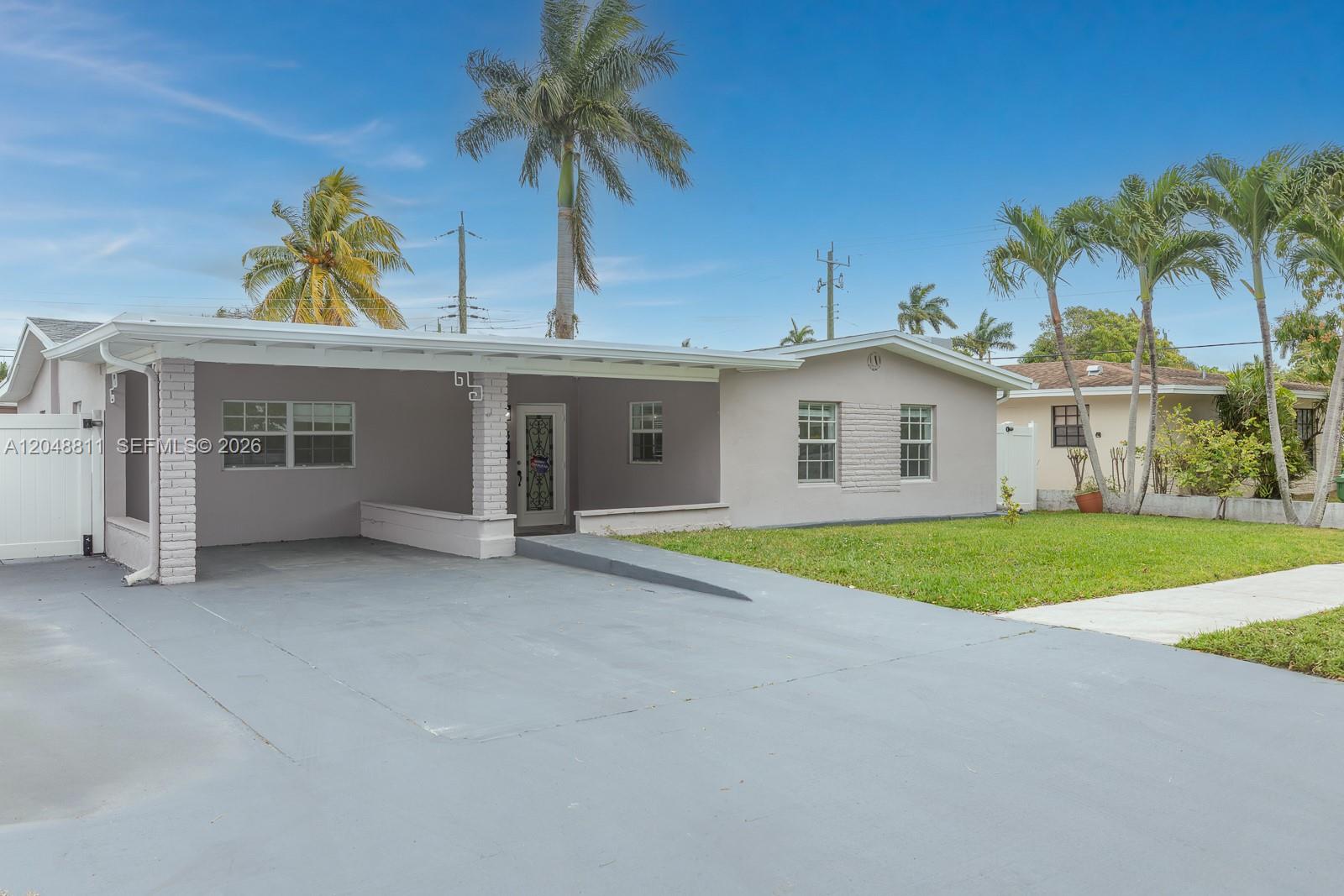 A single-story house with a gray exterior, a covered carport, and a front lawn — 913 NE 2nd St, Hallandale Beach FL 33009, HALLANDALE BEACH, FL