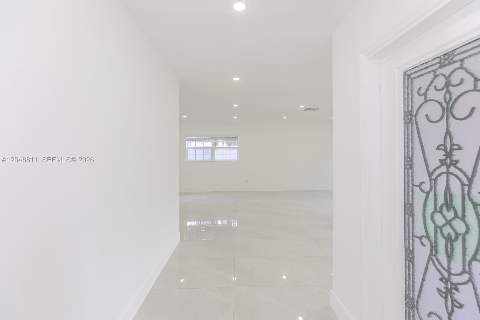A bright, white hallway leads into an open living space with tiled floors — 913 NE 2nd St, Hallandale Beach FL 33009, HALLANDALE BEACH, FL