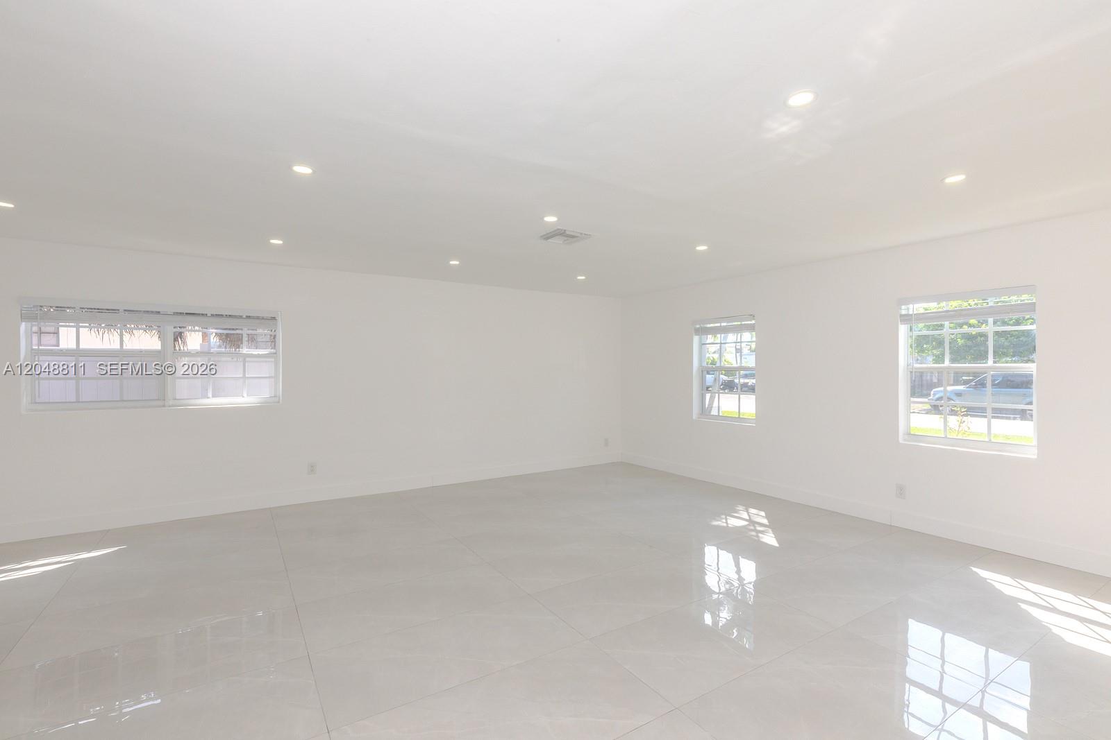 An empty room features white walls, recessed lighting, and large light-colored floor tiles — 913 NE 2nd St, Hallandale Beach FL 33009, HALLANDALE BEACH, FL