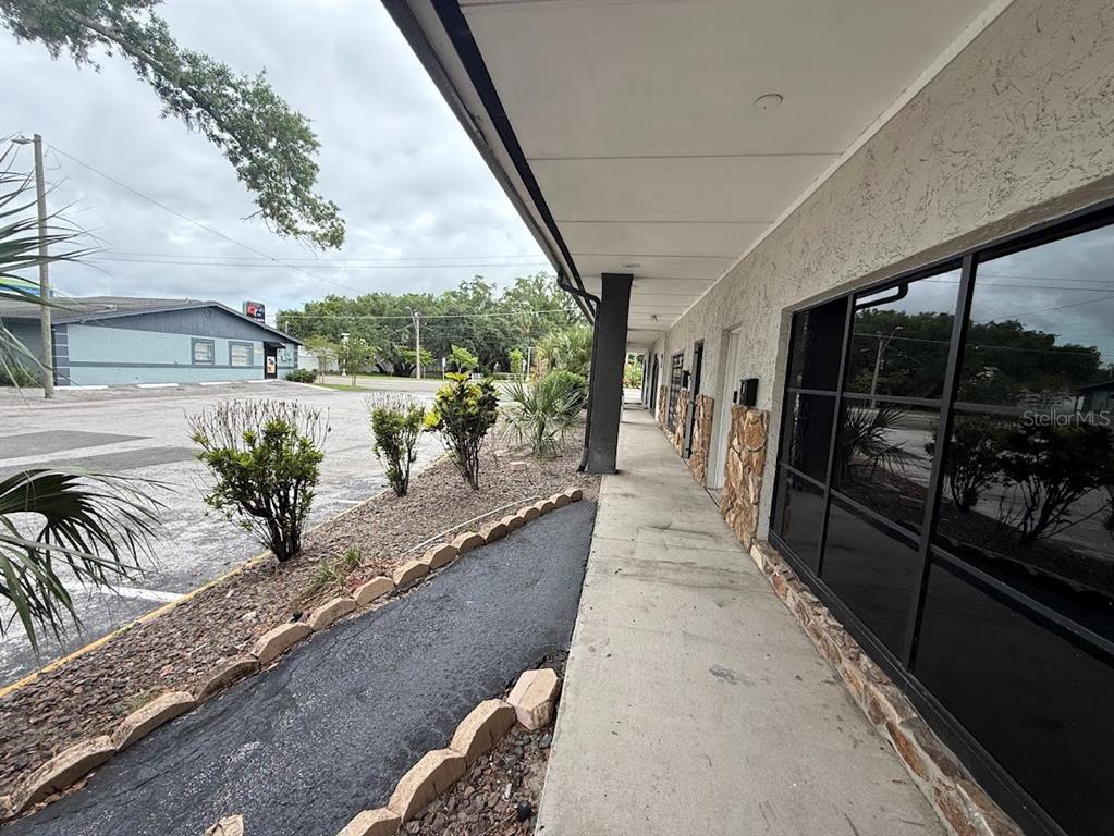 A concrete walkway runs alongside a building exterior with large windows and stone accents — 4211 E BUSCH BOULEVARD UNIT A, TAMPA, FL