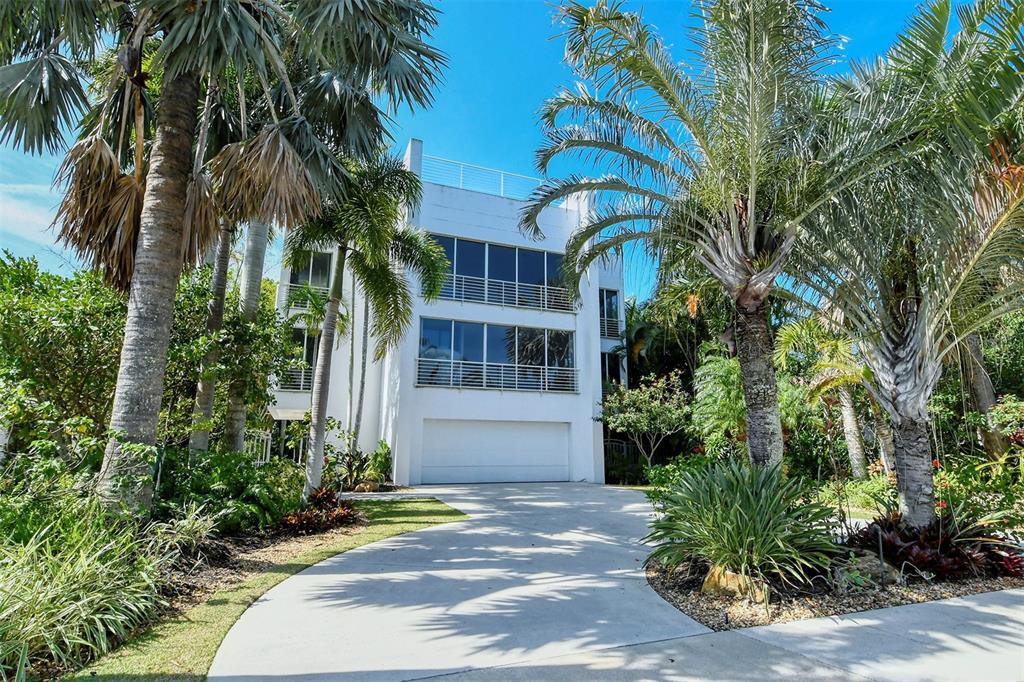 A three-story white house with a garage and balconies surrounded by lush tropical landscaping — 213 N WASHINGTON DRIVE, SARASOTA, FL