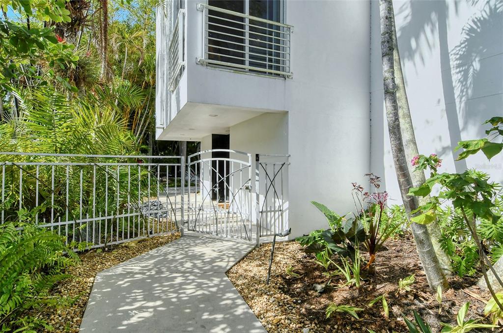 A concrete walkway leads to a white metal gate beside a modern white building exterior — 213 N WASHINGTON DRIVE, SARASOTA, FL