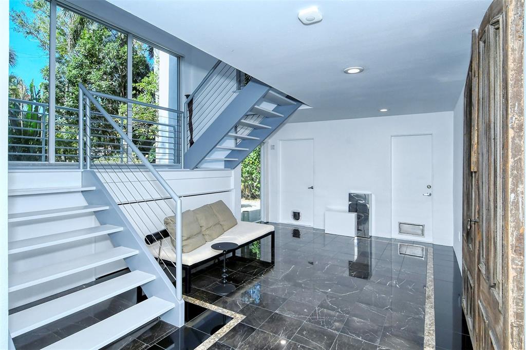 A modern entryway features a white staircase, a small sofa, and dark marble tile flooring — 213 N WASHINGTON DRIVE, SARASOTA, FL