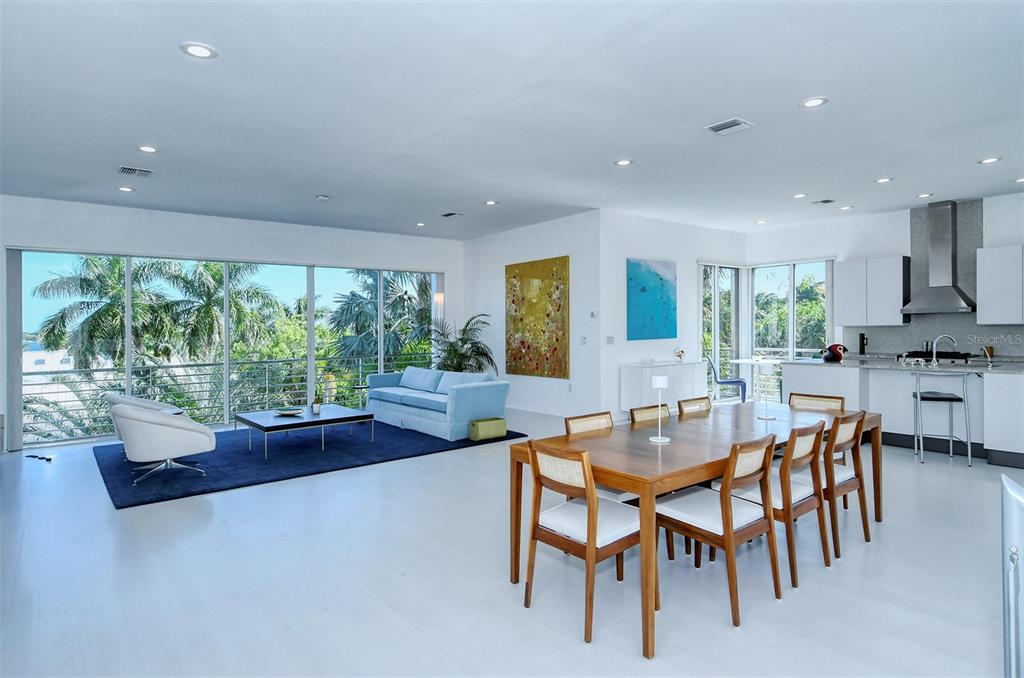 An open-concept living and dining area with white floors, floor-to-ceiling windows, and modern furniture — 213 N WASHINGTON DRIVE, SARASOTA, FL