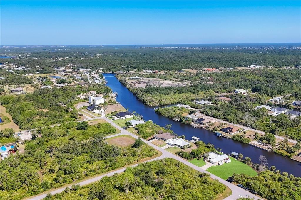 An aerial view shows a canal winding through a residential neighborhood surrounded by dense vegetation — 13564 WAINWRIGHT DRIVE, PORT CHARLOTTE, FL