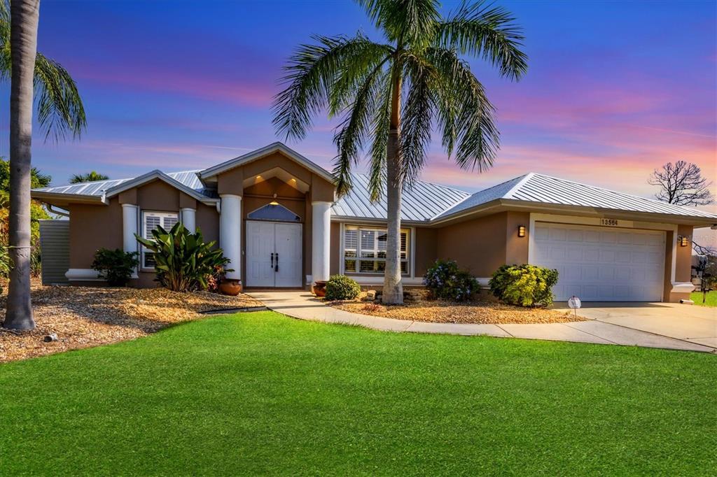 A single-story house with a metal roof, white double doors, and a palm tree — 13564 WAINWRIGHT DRIVE, PORT CHARLOTTE, FL