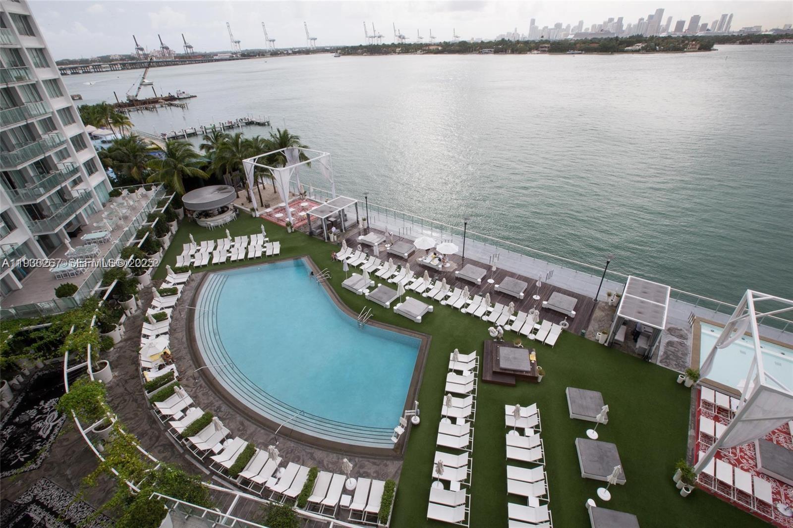 An elevated view shows a swimming pool surrounded by lounge chairs on a waterfront deck — 1100 West Ave # 1220, Miami Beach FL 33139, MIAMI BEACH, FL