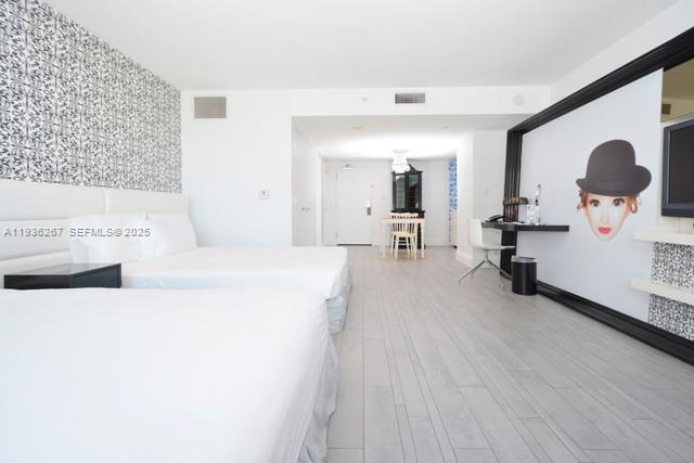 A hotel room features two beds, light wood flooring, and a wall mural of a face — 1100 West Ave # 1220, Miami Beach FL 33139, MIAMI BEACH, FL