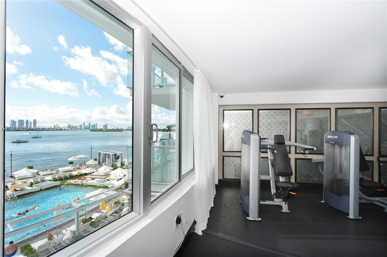 A gym with two Precor machines overlooks a swimming pool and the ocean — 1100 West Ave # 1220, Miami Beach FL 33139, MIAMI BEACH, FL