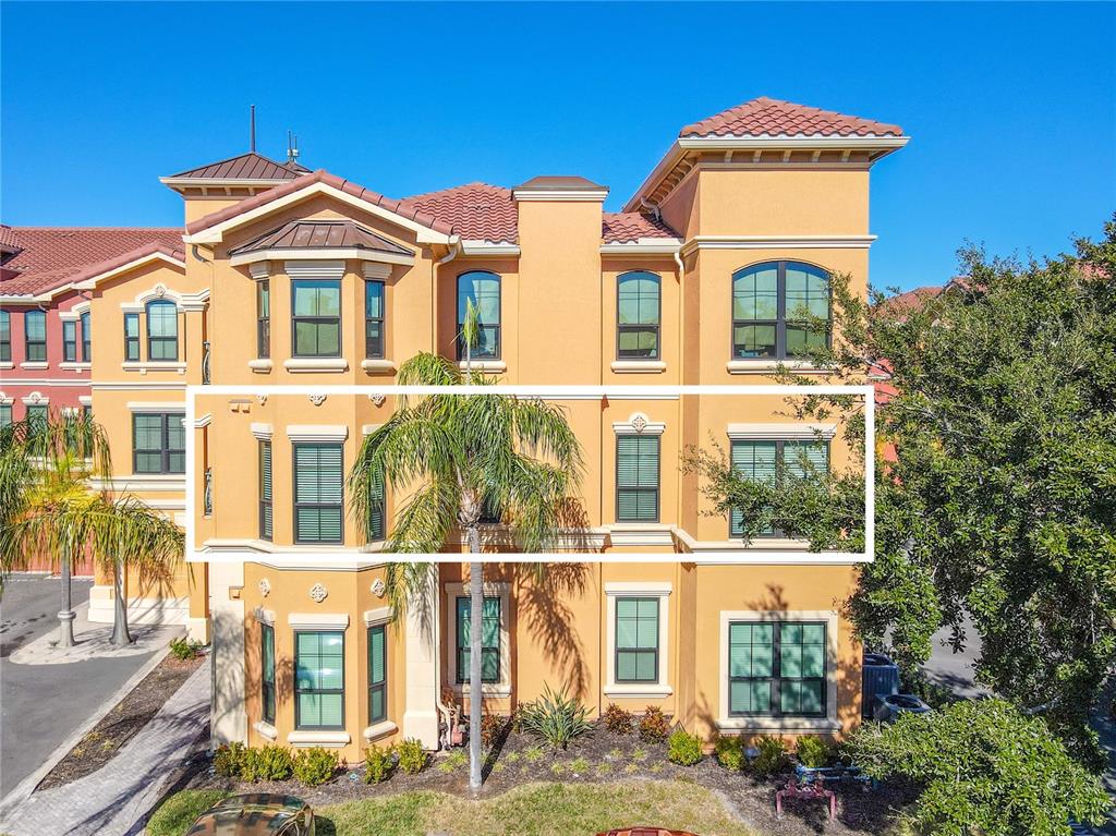 A three-story stucco building with a highlighted middle floor featuring multiple windows and palm trees — 2738 VIA TIVOLI UNIT 220B, CLEARWATER, FL