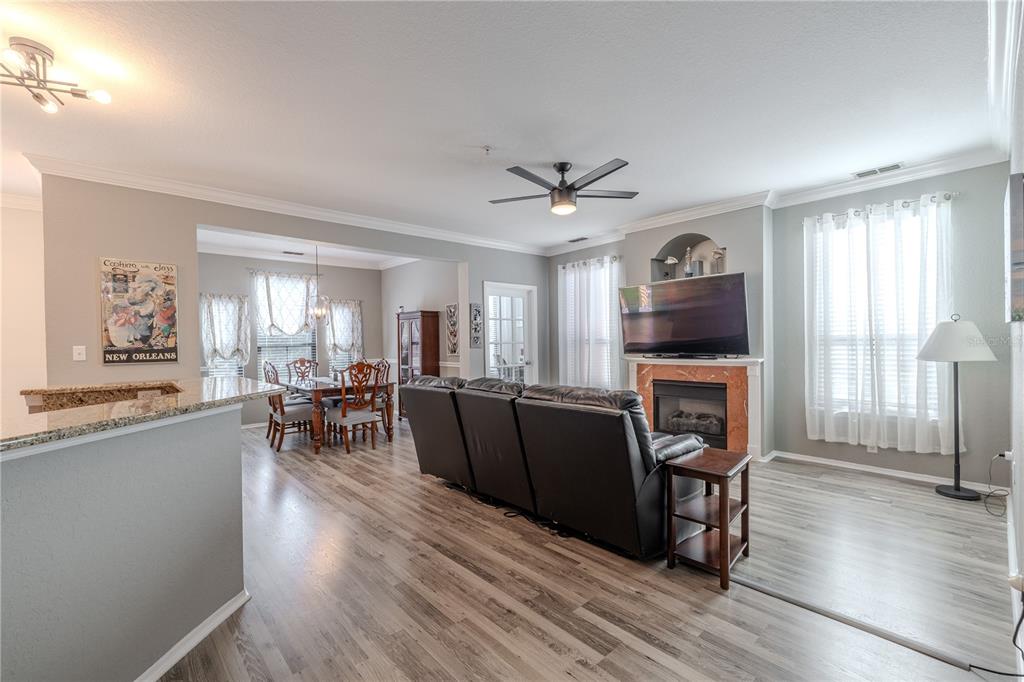 A living room with wood-look flooring, a fireplace, and a dining area in the background — 2738 VIA TIVOLI UNIT 220B, CLEARWATER, FL